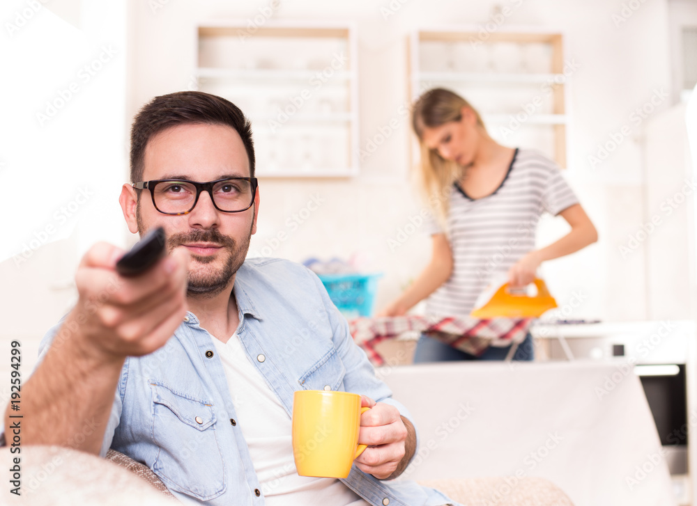 Man watching tv and woman doing housework Man watching tv and woman doing housework