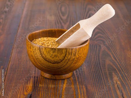 Brown flax seeds in a wooden bowl and spoon on wooden sufface. photo