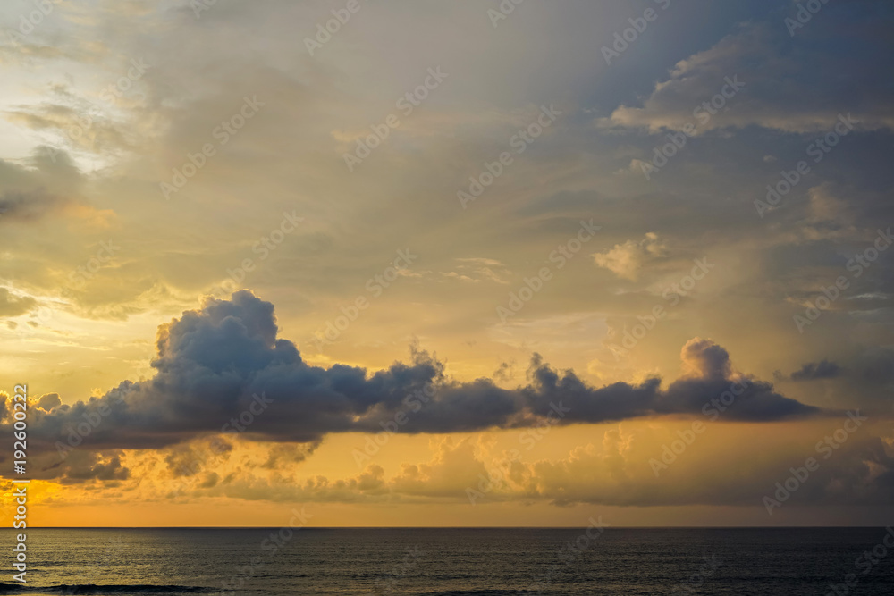 Orange sunset on Uluwatu island of Bali. Large clouds hung over the ocean. Side view with copy space