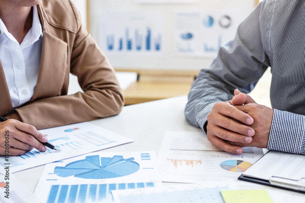 Business team two colleagues discussing new plan financial graph data on office table with laptop and digital tablet Business team two colleagues discussing new plan financial graph data on office table with laptop and digital tablet