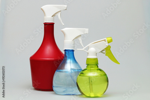 Three multi-colored bottle-spray for cleaning on a white background