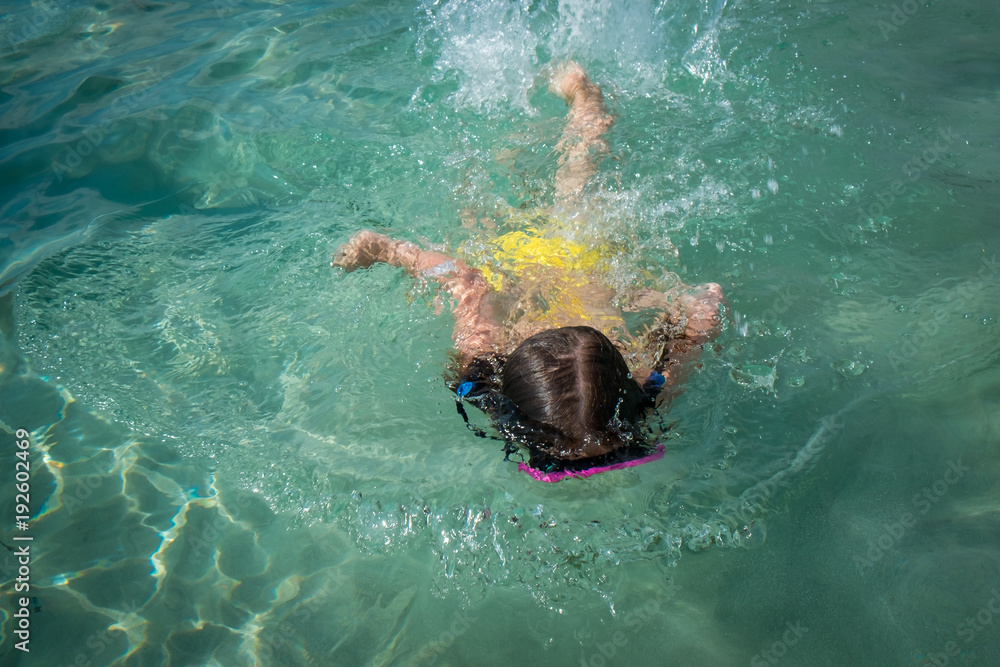 Small girl in a swimming mask swim in clean turquoise water