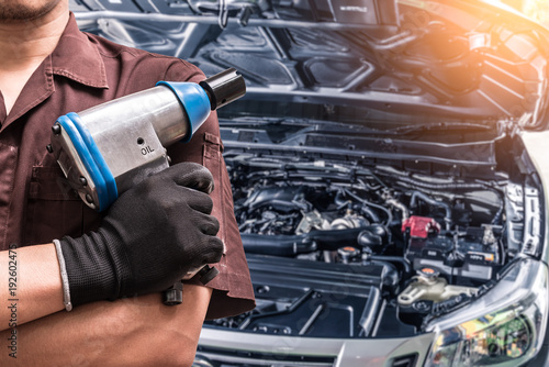 The abstract image of the technician hold the air wrench and blurred engine is backdrop. the concept of automotive, repairing, mechanical, vehicle and technology.