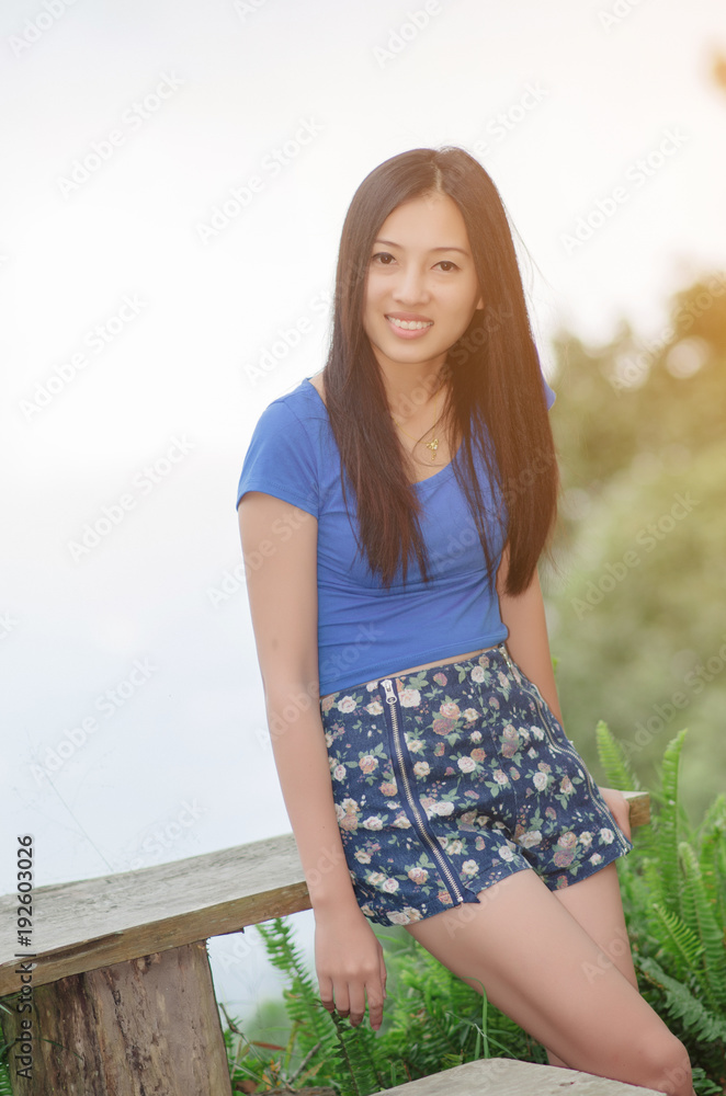Naklejka premium Asia young shy women sitting and smile on wood long chair