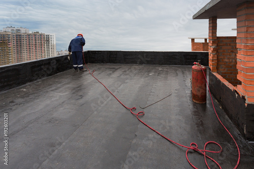 A worker puts waterproofing on the roof.