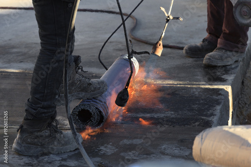 Laying of roofing felt from the roll with a flame from the burner close-up. photo