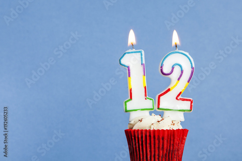 Number 12 birthday candle in a cupcake against a blue background photo