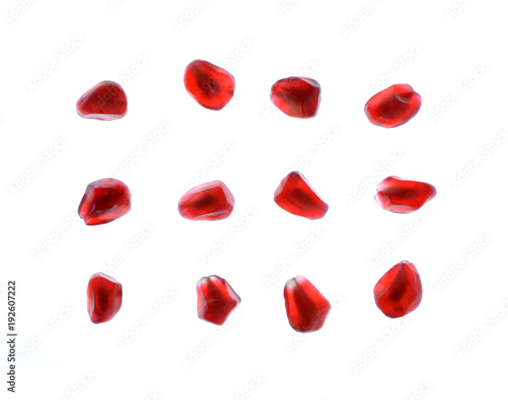 A group of red pomegranate seeds arranged on white background A group of red pomegranate seeds arranged on white background