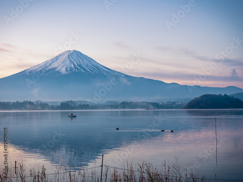sunrise landscape view from kawaguchi lake with motion blur from group of duck foreground and fuji mountain background with fog from japan