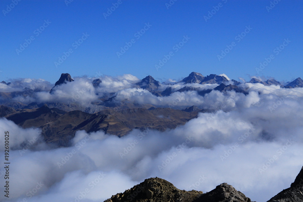 High mountain peaks in Pyrenees. Sea of clouds over snowy landscape.