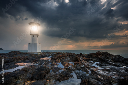 Lighthouse raincloud on the rock under raincloud.