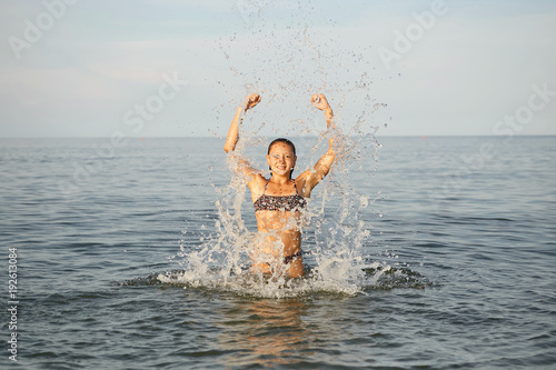 Spray with water. Girl having fun bathing in the sea.