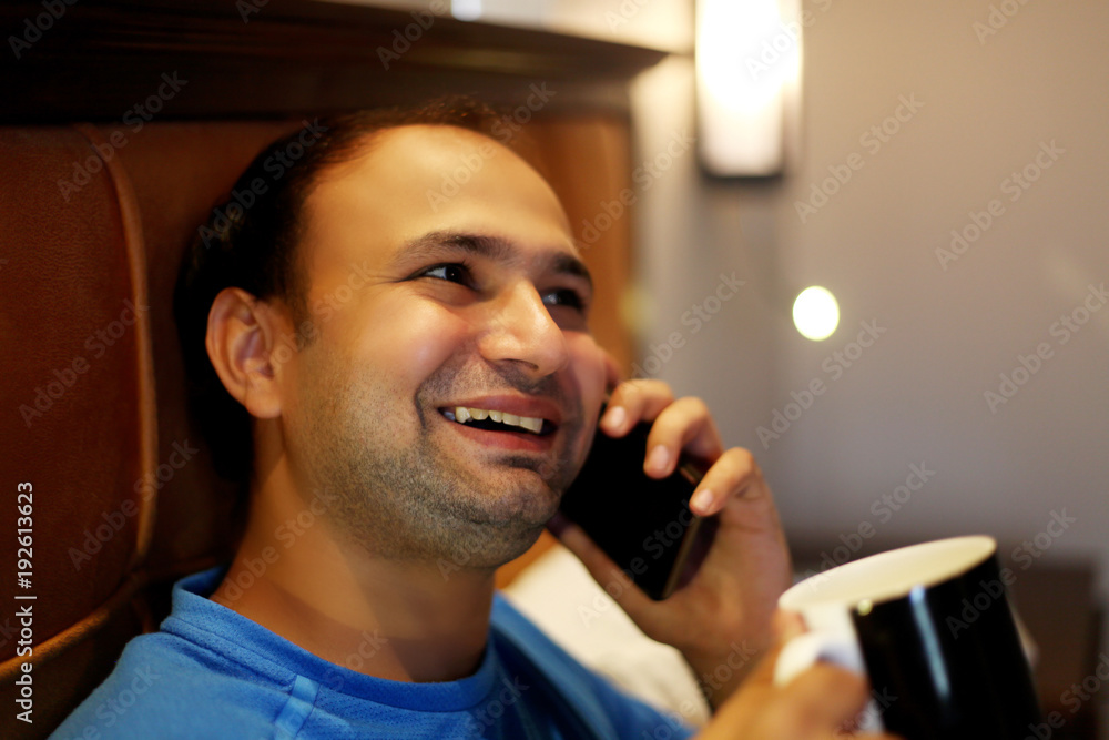  Young men of Indian ethnicity sitting on the bed in hotel room