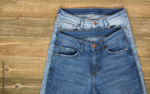 top view of two pairs of high waist women jeans front view on brown wooden background. jeans shop.