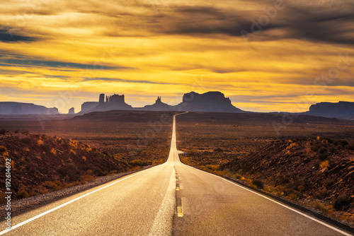 Desert road leading to Monument Valley at sunset