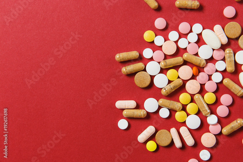Medication white colorful round tablets arranged abstract on red color background. Aspirin, capsule pills for design. Health, treatment, choice healthy lifestyle concept. Copy space advertisement.