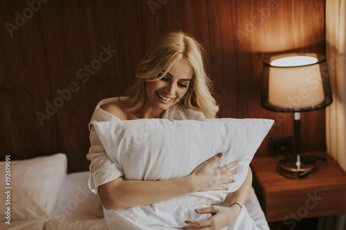 Happy blonde woman hugging her pillow at home in the bedroom © BGStock72