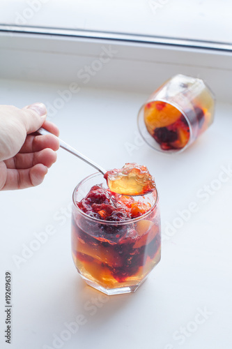 fruit jelly in serving glasses, pieces of jelly on the spoon, life style photo
