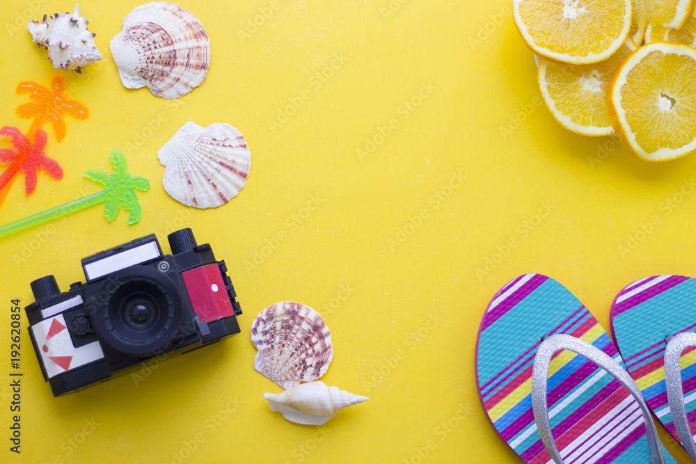 Bright yellow one-color background with slices of orange, old vintage camera, sea shells and beach shoes, top view. Travel or tourism concept. Space for a text or product display. Bright yellow one-color background with slices of orange, old vintage camera, sea shells and beach shoes, top view. Travel or tourism concept. Space for a text or product display.