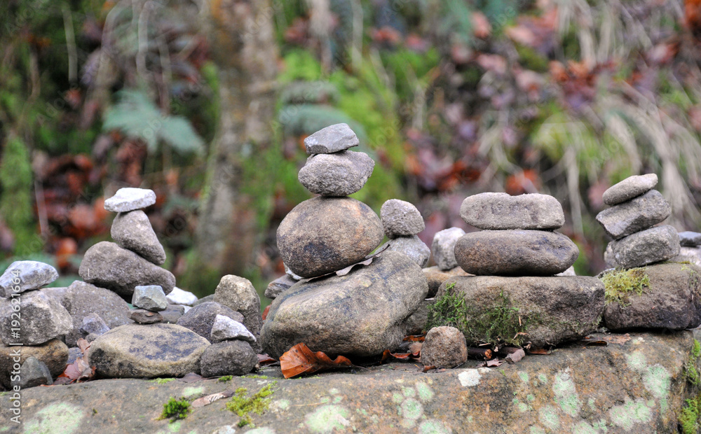 stacked towers of stones and pebbles in woodland on a large rock stacked towers of stones and pebbles in woodland on a large rock