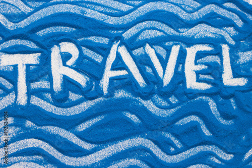 Travel inscription on a blue colored sand with waves, top view, flat lay photo