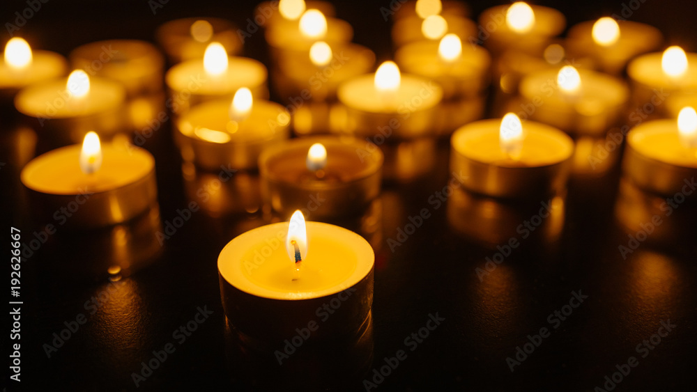 Burning candles. Shallow depth of field. Many christmas candles burning at night. Abstract candles background. Many candle flames glowing on dark background. Close-up.