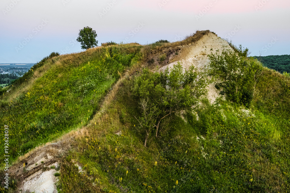 Ancient Cretaceous overgrown high hill with outcrops of chalk. Territory natural archaeological monument - Krapivenskoye ancient settlement, Belgorod region, Russia. Evening time.