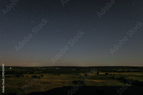 View of green forest-steppe plain at night. Landscape from height with starry sky over the horizon.