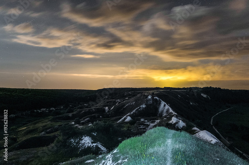 White cretaceous hills at night. Night landscape with chalk mountains under cloudy sky. Natural archaeological monument - Krapivenskoye ancient settlement, Belgorod region, Russia.