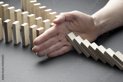 The financial crisis and economic decline. Businessman hand stop domino continuous tipping or risk. 