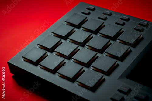 black modern musical instrument, sampler on an intense red background photo