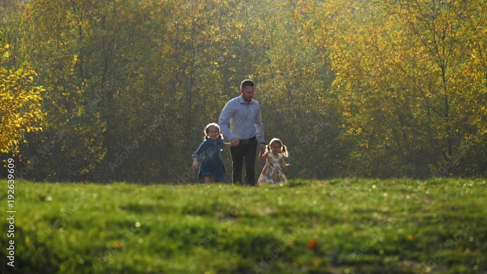 Father with his two daughters running in the meadow. Father with his two daughters running in the meadow.