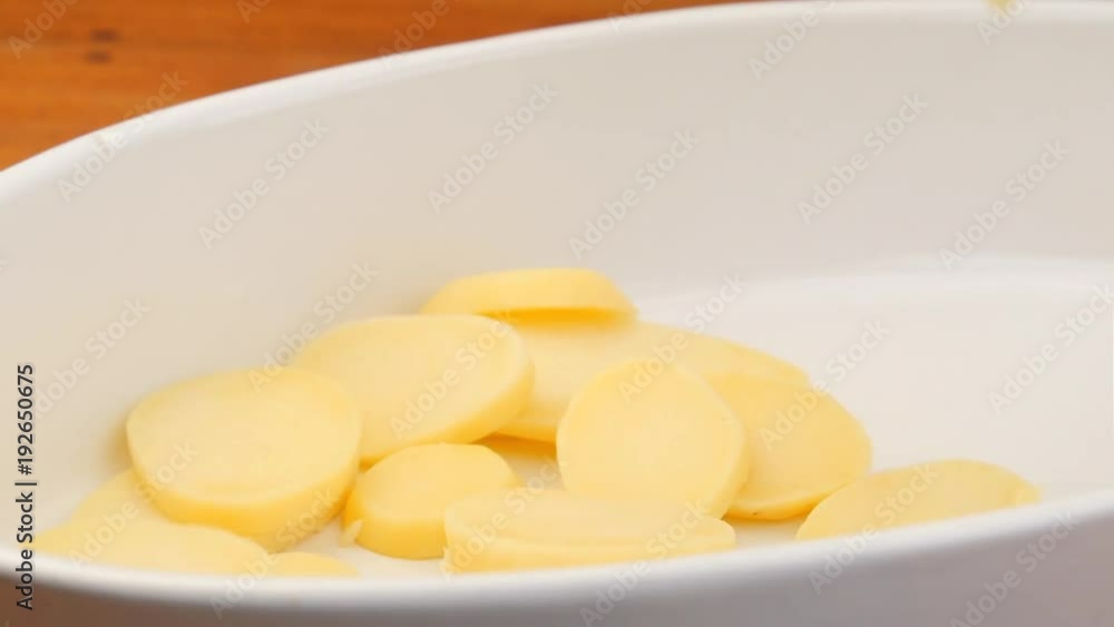 Fresh sliced potatoes dropping in oven dish while preparing a meal. Slow motion footage. Fresh sliced potatoes dropping in oven dish while preparing a meal. Slow motion footage.