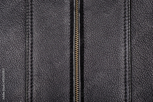 The surface texture is made of genuine black leather with two seams with a double stitch and a zipper in the center. Close-up.