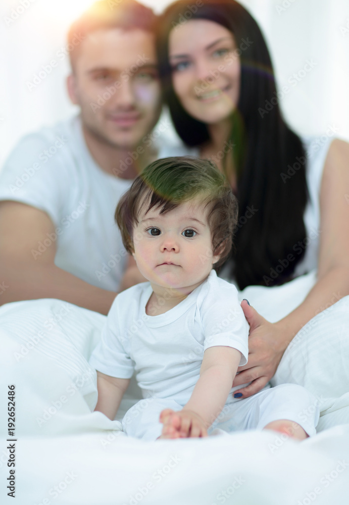 Happy couple and son sitting in bed