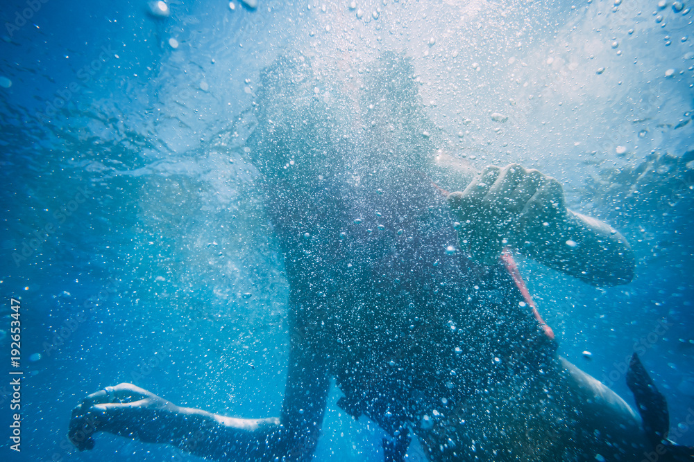 The silhouette of an attractive slim woman under water. The beauty of the ocean world. Ideal background for the different kinds of marine collages and illustrations in blue shades.