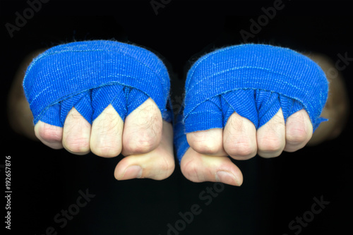 hands of a fighter blue bandages copyspace, black background, selective focus