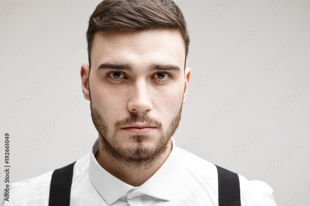 Studio shot of serious young unshaven Caucasian male entrepreneur staring at camera with deep in thoughts look, thinking over some business problem. People, modern lifestyle, job and career concept Studio shot of serious young unshaven Caucasian male entrepreneur staring at camera with deep in thoughts look, thinking over some business problem. People, modern lifestyle, job and career concept