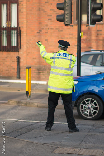 policeman traffic cop gesticulates whilst directing and managing traffic on busy road 
