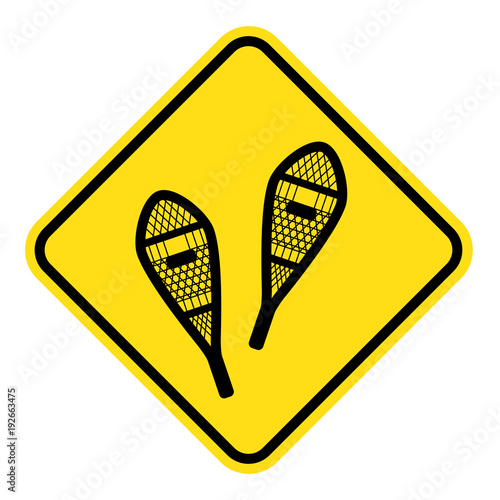 yellow sign for snowshoeing route. old style traditional snowshoes. winter outdoor activity.