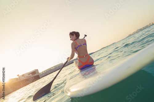 Sexy woman at the beach with board at the sunset