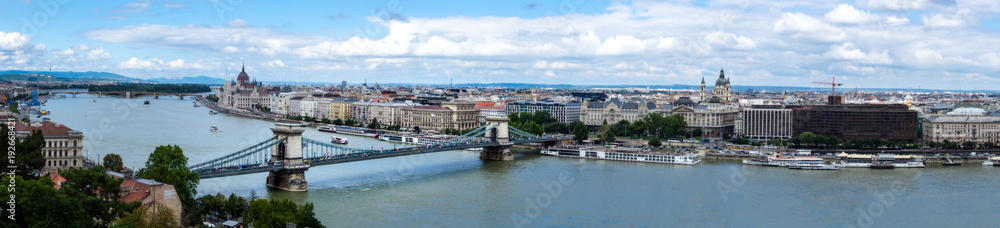 Wide panorama of Budapest with visible bridges, ships on the river and historic buildings and the parliament building on a summer sunny day