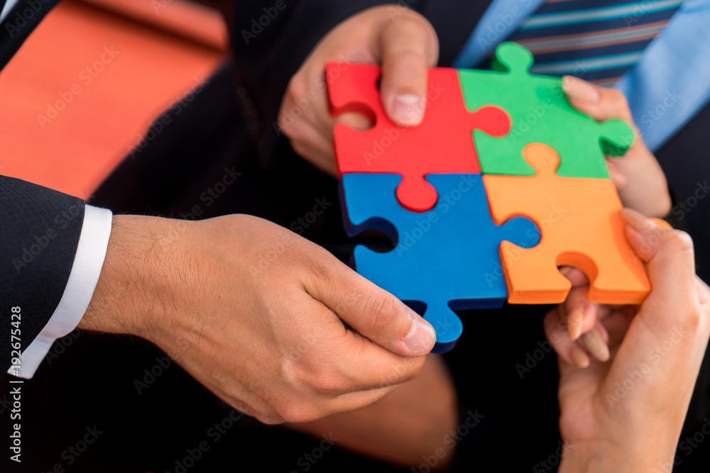 Business people solving jigsaw puzzle. Team holding colorful puzzle pieces in hands Business people solving jigsaw puzzle. Team holding colorful puzzle pieces in hands