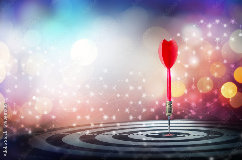 Close up shot red dart arrow on center of dartboard over bokeh background Close up shot red dart arrow on center of dartboard over bokeh background