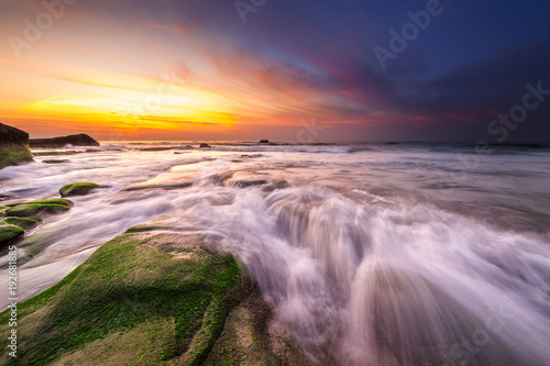 vibrant sky suring sunset with waves trails. image content soft focus due to slow shutter.