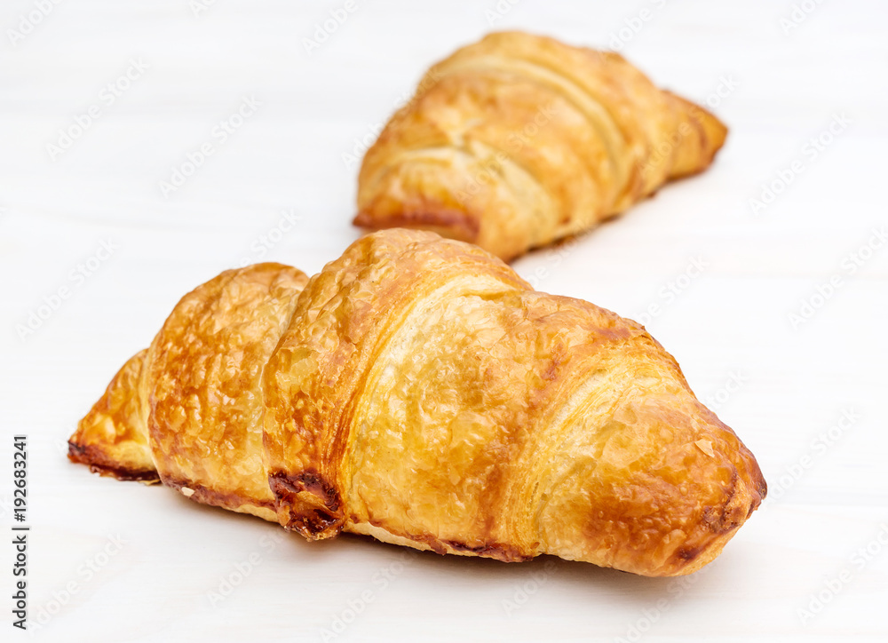 Two fresh croissants on white wooden table. Close up.