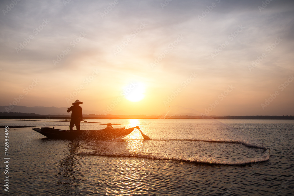 Fototapeta premium Asian fisherman throwing fishing net in lake at sunrise time.(Lifestyle of the population living in the river)