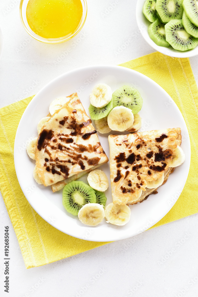 Crepes with banana, kiwi slices and chocolate sauce