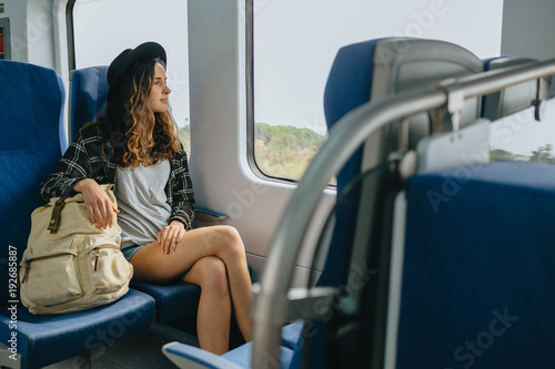 Beautiful girl in hat with a backpack sitting in the train. Traveling, journey.