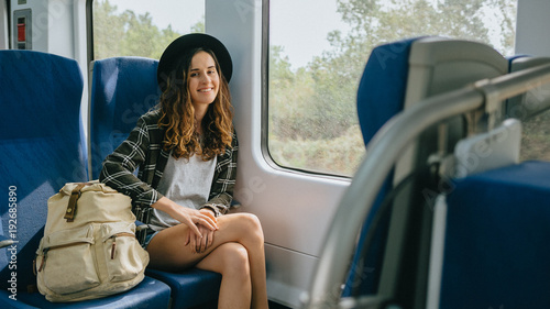 Beautiful girl in hat with a backpack sitting in the train. Traveling, journey.